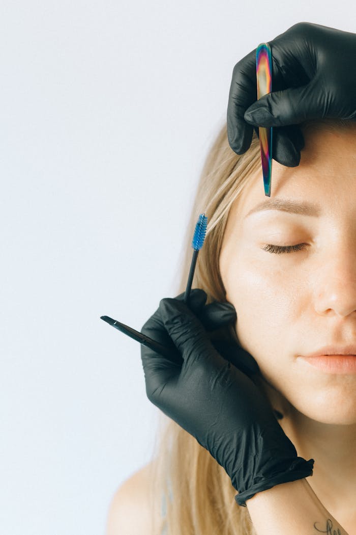 Close-up of a woman receiving professional eyebrow and lash treatment in a beauty salon.